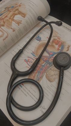 a stethoscope sitting on top of an open book next to medical diagrams