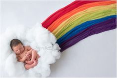 a newborn baby is sleeping in a cloud with a rainbow behind it on a white backdrop