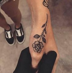 a person with a flower tattoo on their left foot and one hand holding the other