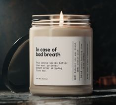 a candle that is sitting on a table next to a black container with the words in case of bad breath