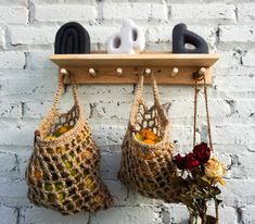 two crocheted purses hanging on a brick wall with flowers in the foreground