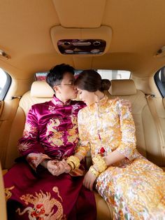 a man and woman sitting in the back of a car with their hands on each other