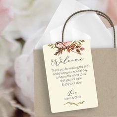 a paper bag with a welcome message on the front and back, sitting next to some flowers