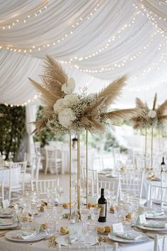 the tables are set with white linens, gold chargers and tall centerpieces