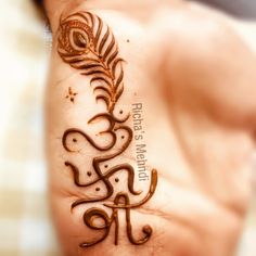 a woman's hand with a henna tattoo on it and a feather in the middle