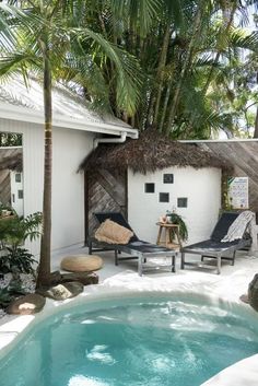 an outdoor hot tub in the middle of a tropical garden with chairs and palm trees