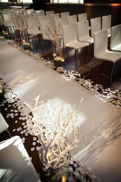 a living room with white furniture and flowers on the floor, along with candles in vases