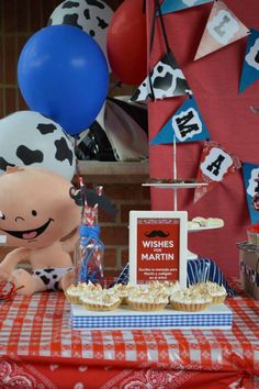 a table topped with cake and balloons on top of a red checkered table cloth