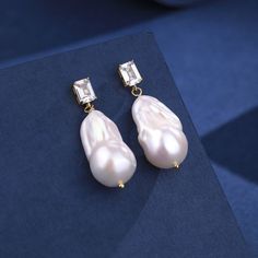 Enhance your special occasion attire with our 11-13mm Baroque Pearl Earrings, perfect for weddings, banquets, or casual elegance. These fashion-forward earrings showcase large baroque pearls, exquisitely paired with sparkling cubic zirconia in white or blue. The high luster of the pearls combined with the meticulous craftsmanship and silver settings, plated in 18K gold, offers a touch of simple sophistication. Product Details: Pearl Type: Freshwater Baroque Pearls Pearl Size: 11-13mm Accents: Cu Baroque Pearl Earrings, Luxurious Design, Cz Earrings, Pearl Types, Pearl Gemstone, Blue Style, Pearl Size, Crystal Rings, Silver Pearls