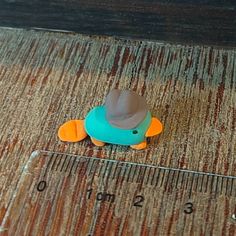 a toy duck with a hat on it's head sitting next to a ruler