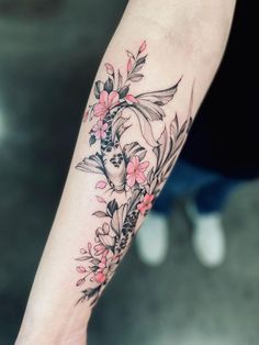 a woman's arm with flowers and leaves on it