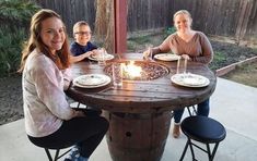 three people sitting around a table with plates on it