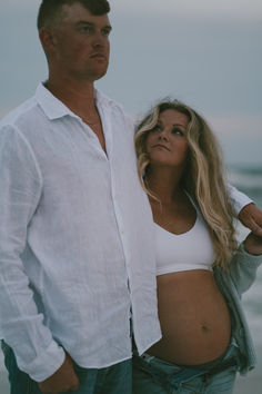 a man and woman standing next to each other on the beach