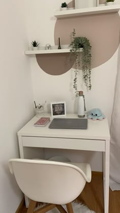 a white desk and chair in a small room with shelves above it, along with plants on the wall