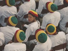 a group of people sitting next to each other in white shirts and green and yellow hats