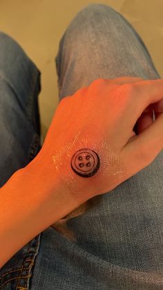 a person with a smiley face tattoo on their left arm and wrist, sitting down