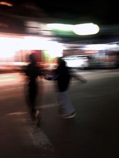 blurry image of two skateboarders riding down the street in front of a building