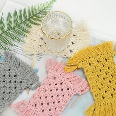 four crocheted scarves sitting on top of a table next to a cup