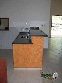 an empty kitchen with black counter tops and tile flooring