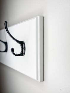 a black hook is attached to a white wall