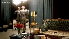 a man standing in front of a couch next to a table with flowers on it