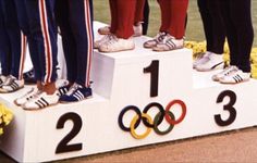 four people standing on top of a podium with their feet in the air and numbers painted on them