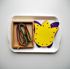 a white tray with a yellow and purple bird shaped object in it's box