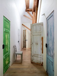 an empty hallway with two green doors and a bench in the middle, along with wooden beams on the ceiling