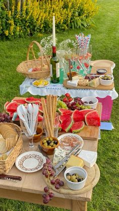 an outdoor picnic with watermelon, grapes and cheeses on the side table