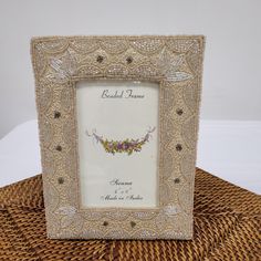 a white and gold beaded frame sitting on top of a wicker table