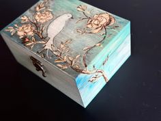 a box with flowers painted on it sitting on top of a black table next to a pair of scissors