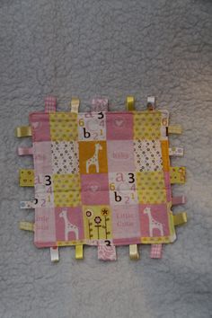 a pink and yellow patchwork baby blanket with numbers on the bottom, along with giraffes