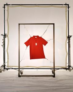 a t - shirt is hanging in front of a photo frame with clothes on it