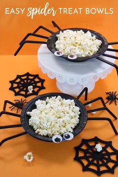 two black plates filled with popcorn and spooky spider decorations on top of an orange table