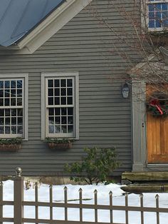 a snowboarder is standing in front of a house with two windows and a fence