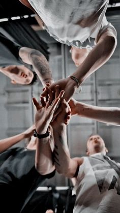 several people stacking their hands on top of each other in the middle of a group