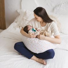 a woman holding a baby while sitting on a bed