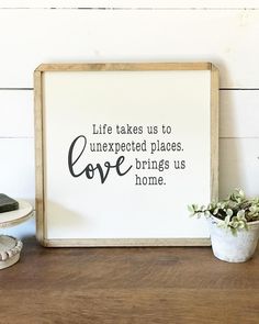 a wooden frame with a quote on it next to a potted plant