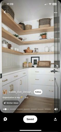 an image of a kitchen with white cabinets and wood shelves on the left side of the screen