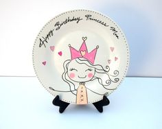 a white plate with a pink princess design on the front and black legs that says happy birthday princess