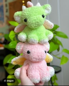 three stuffed animals are stacked on top of each other in front of a potted plant