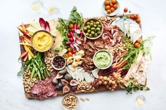 a platter filled with meats, vegetables and dips