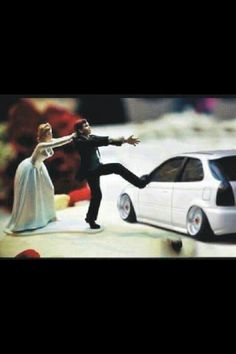 a bride and groom figurines on top of a wedding cake next to a toy car