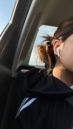 a woman wearing ear buds in the back seat of a car