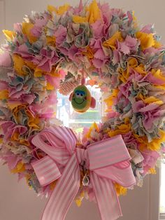 a pink and yellow wreath hanging on the side of a door