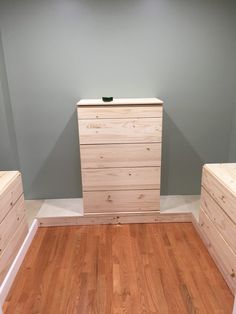 an empty room with wooden drawers and hard wood flooring on the ground, in front of a gray wall