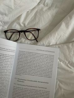 an open book with glasses on top of it