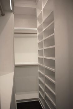 an empty walk in closet with white shelves