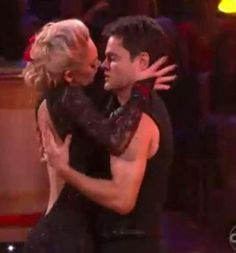 a man and woman dance together on the dance floor in front of a microphone with their arms around each other