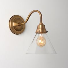 an antique brass wall light with clear glass shade